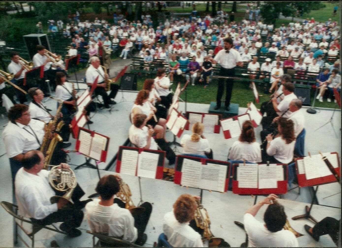 A view from the back row of the band showing a full audience in the park listening to the band play.