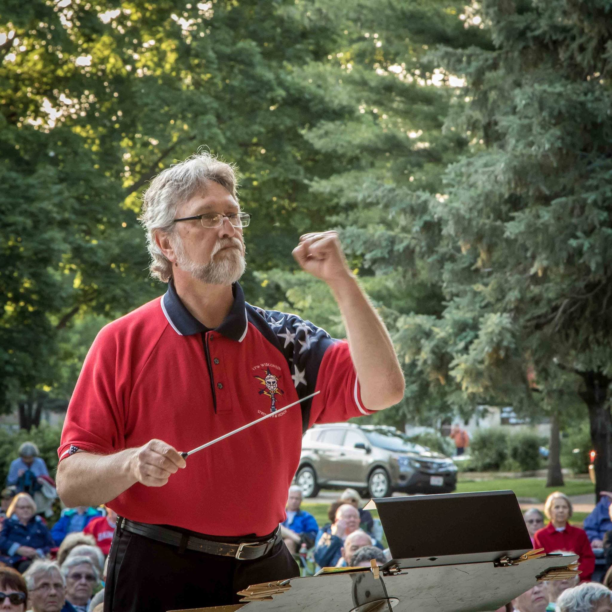 Greg Sauve conducting in a red, white, and blue VFW Wisconsin polo shirt