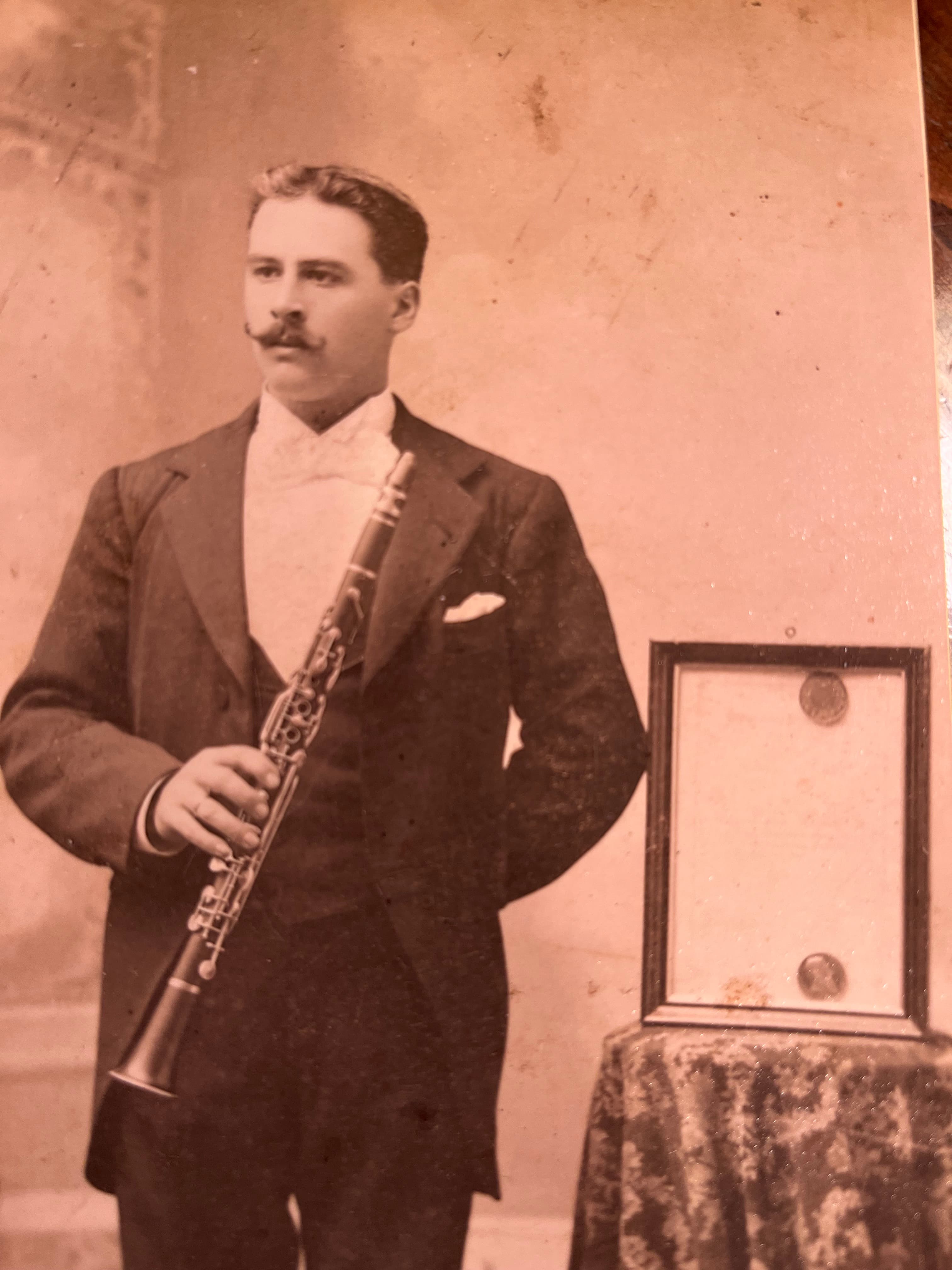 A sepia toned image of M.J. Heynen posing with a clarinet looking off to the side